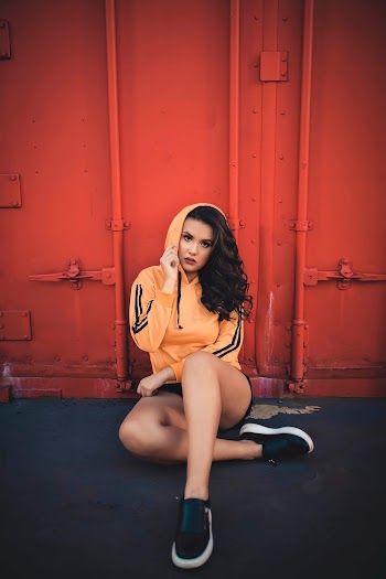 Woman Sitting in front of a Red Shipping Container