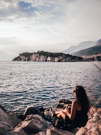 Woman Sitting In Front Of Body Of Water