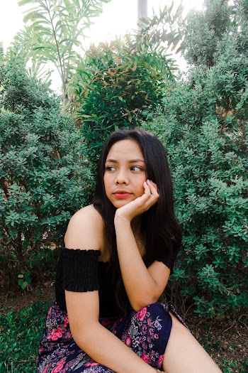 Woman Sitting in Front of Green Plant Resting Her Face on Her Hand
