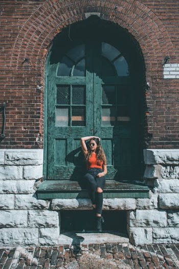 woman sitting in front of green wooden door