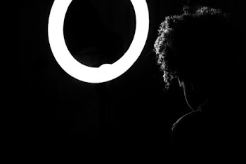 Woman Sitting in Front of Round Light Inside Dark Room