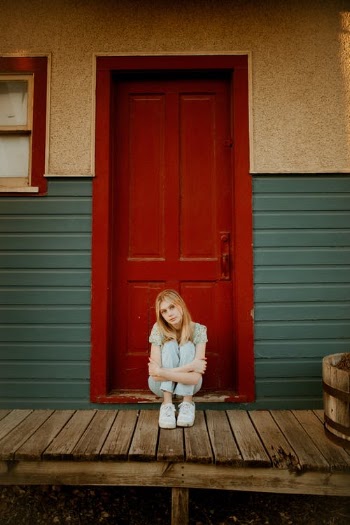 Woman Sitting in front of the Red Door with Her Knees Up · Free Stock Photo