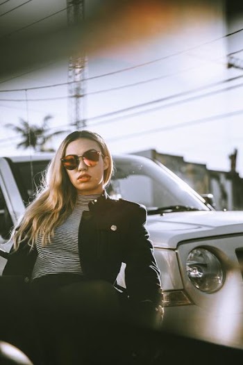 woman sitting in front of white car during daytime