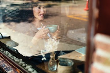 woman sitting inside train holding teacup