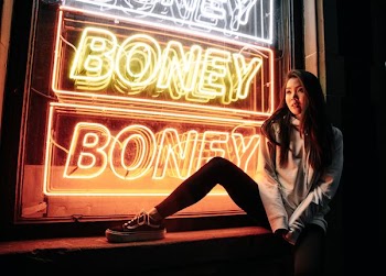 woman sitting near Boney neon light signage