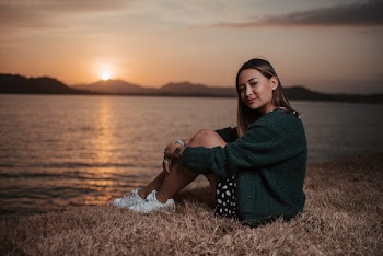 Woman Sitting Near Calm Body of Water during Sunset