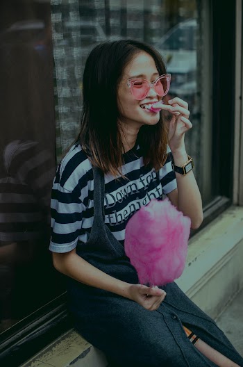 Woman Sitting Near Glass Wall Holding Cotton Candy