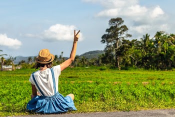 Woman Sitting Near Grass Field Showing Peace Hand Sign