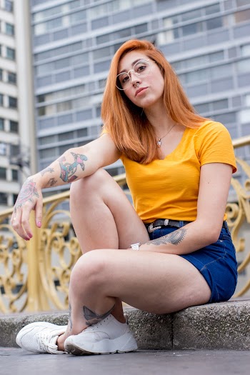 Woman Sitting Near Gray High-rise Building
