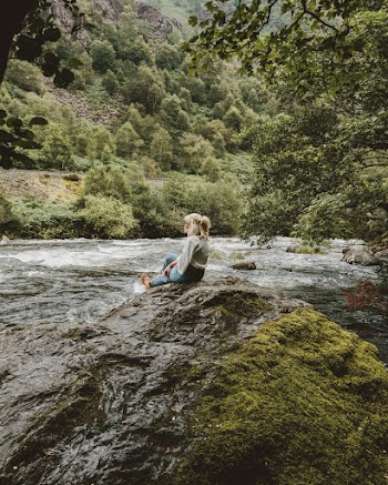 Woman Sitting Near On A Rock Formation By the River