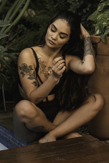 Woman Sitting Near Potted Plants While Closing Her Eyes