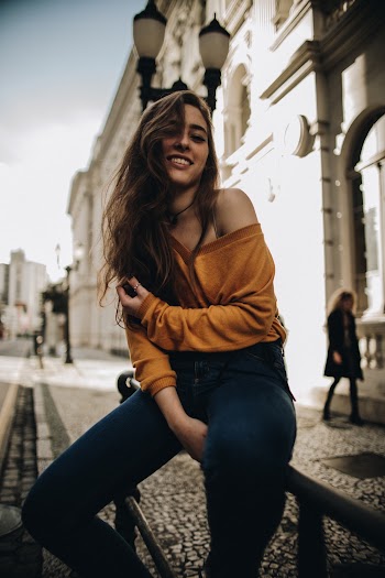 Woman sitting near road and building