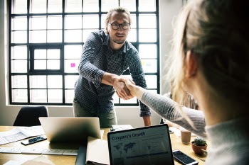 Woman Sitting Near Table Shaking Hands With a Guy Stranding Opposite