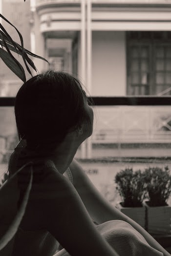 Woman Sitting Near Window Looking Outside