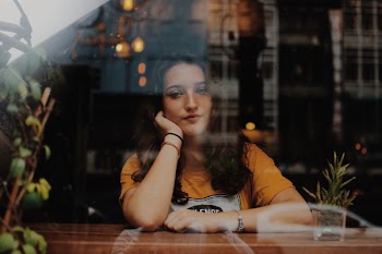 woman sitting next to table with hands on cheek