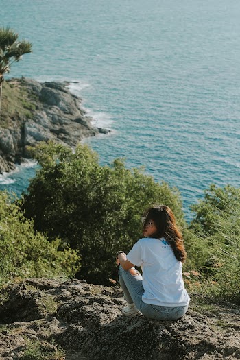 Woman Sitting On A Mountain Cliff Overlooking The Sea