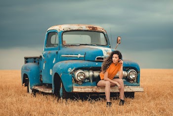 Woman Sitting On A Vehicles Bumper