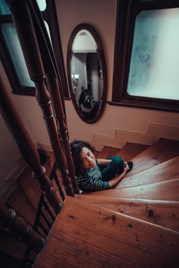 Woman Sitting on a Wooden Spiral Staircase