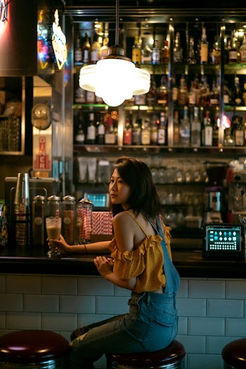 Woman Sitting on Bar Stool While Holding Glass