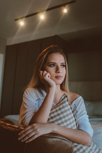 Woman Sitting on Bed Hugging A Pillow