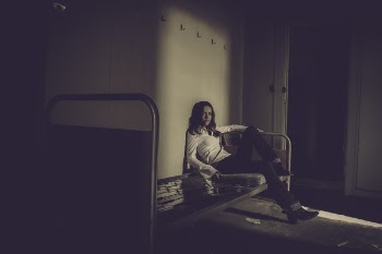Woman Sitting on Bed Inside Empty Room