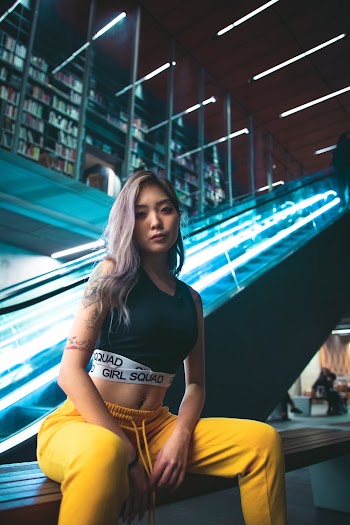 Woman Sitting on Bench Near Escalator