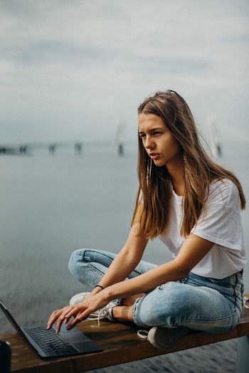 Woman Sitting on Bench While Using Laptop