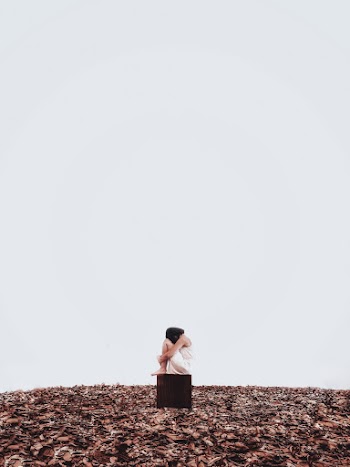 Woman Sitting on Black Box in the Middle of Field
