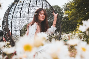 Woman Sitting on Bobble Chair Surrounded by Flowers Near Trees
