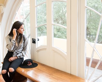 Woman Sitting on Brown Bench Beside Closed Door