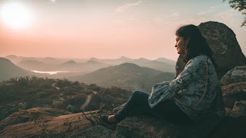 Woman Sitting on Brown Rock