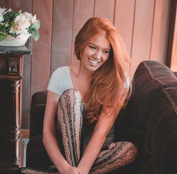 Woman Sitting on Brown Sofa Near Brown Wooden Wall