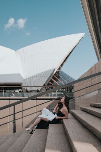 woman sitting on brown stairs under blue sky at daytime