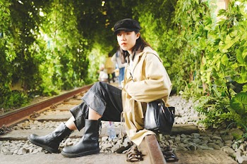 Woman Sitting on Brown Train Rail Near Green Trees