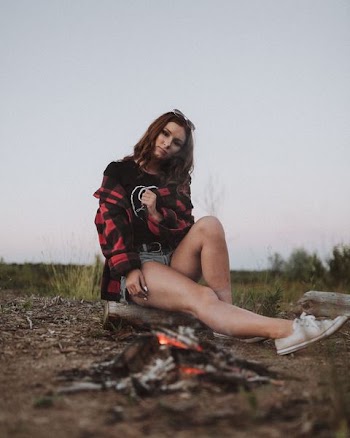 woman sitting on brown wood log in front of bonfire during daytime