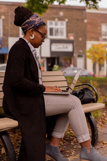 Woman Sitting on Brown Wooden Bench Using Macbook Pro