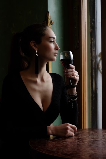 Woman Sitting on Chair Beside Table While Holding Wine Glass
