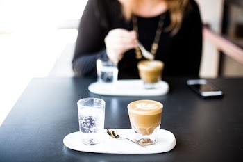 woman sitting on chair in front of table with two glasses with liquid inside