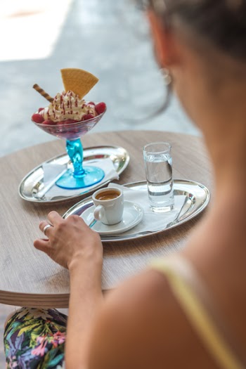Woman Sitting on Chair While Her Left Hand Beside Coffee Mug on Gray Tray