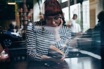 Woman Sitting On Chair While Reading Book