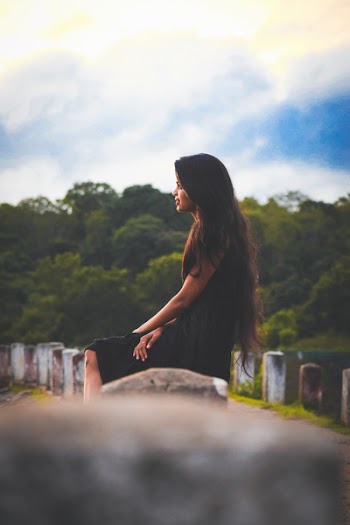 Woman Sitting on Concrete Pillar