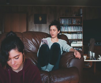Woman Sitting On Couch While Using Smartphone