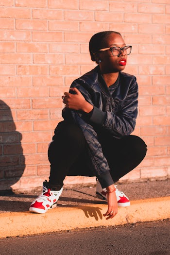Woman Sitting on Curb Near Brown Bricked Wall
