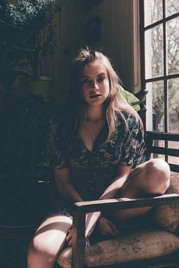 woman sitting on daybed near window during daytime