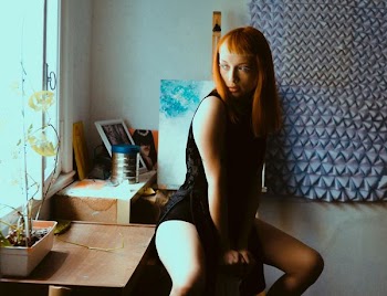 woman sitting on drawer near window