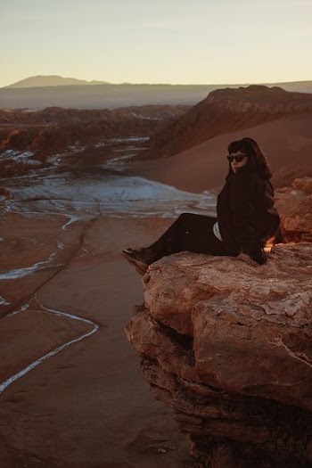woman sitting on edge of mountain