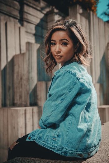 woman sitting on fence facing to the camera during dayime
