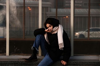 woman sitting on fence near glass window