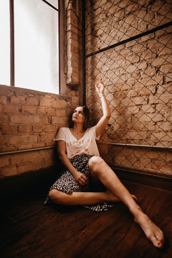 Woman Sitting on Floor Beside Glass Window