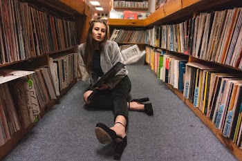 woman sitting on floor between bookshelves
